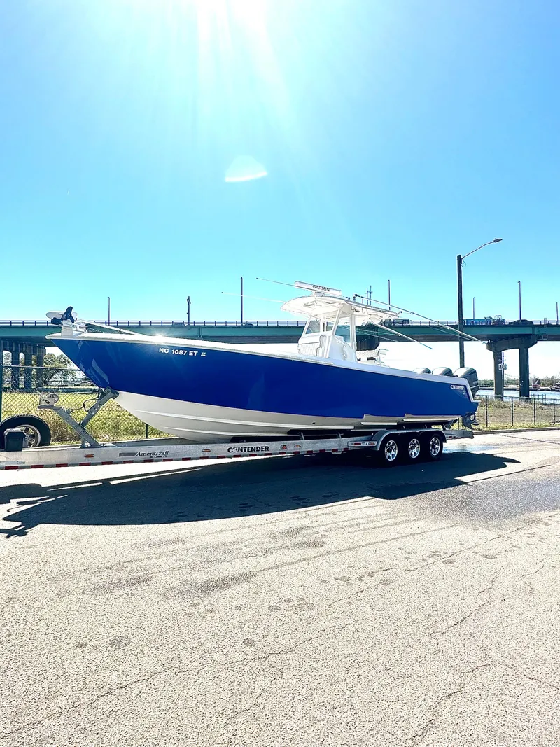 Slide: The Image of 2015 Contender 35 ST boat on trailer, parked near a bridge under clear blue sky. - 9