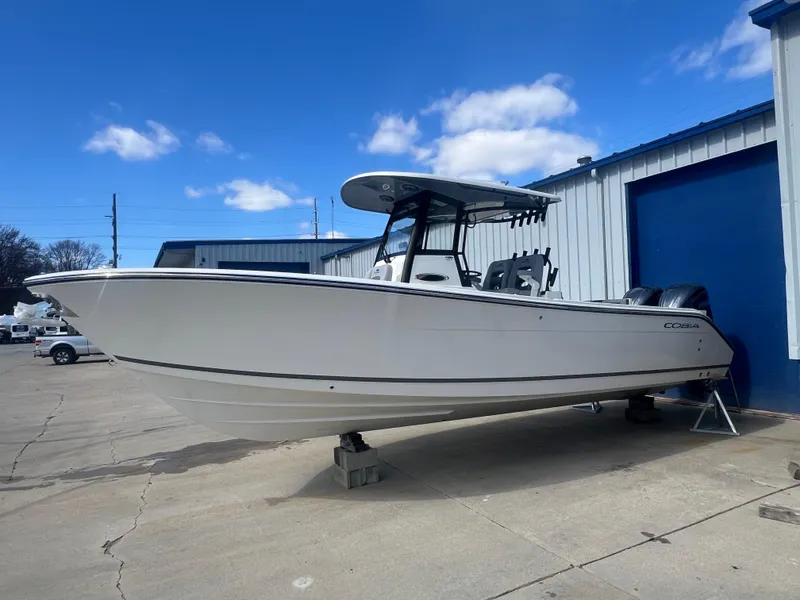 The Image of 2025 Cobia 285 Open Center Console boat on display outside a warehouse. - 1