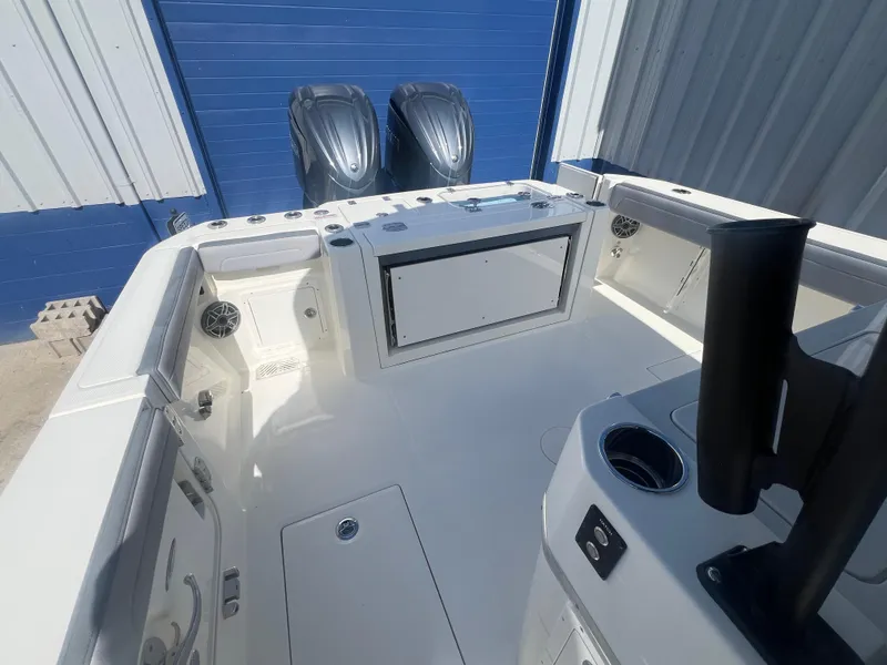 Slide: The Image of 2025 Cobia 285 Open Center Console boat interior with dual engines, docked in a marina. - 7