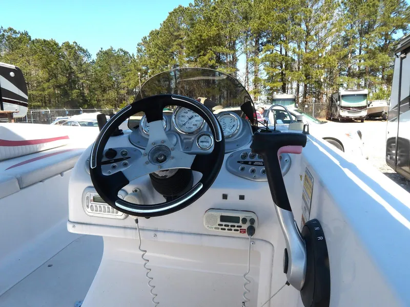 Slide: The Image of 2008 Starcraft Stardeck 200 boat dashboard with steering wheel and controls, surrounded by trees. - 12