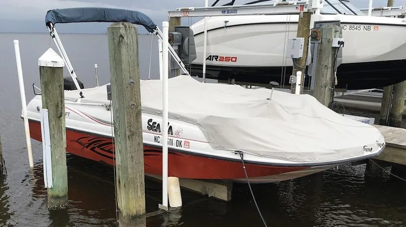 Slide: The Image of 2008 Starcraft Stardeck 200 boat docked with cover, featuring red and white design. - 3