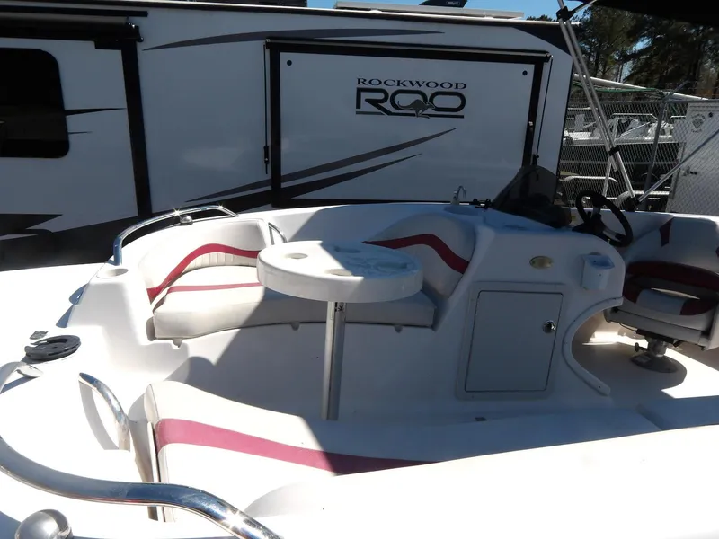Slide: The Image of 2008 Starcraft Stardeck 200 boat interior with seating and table, parked near Rockwood camper. - 9