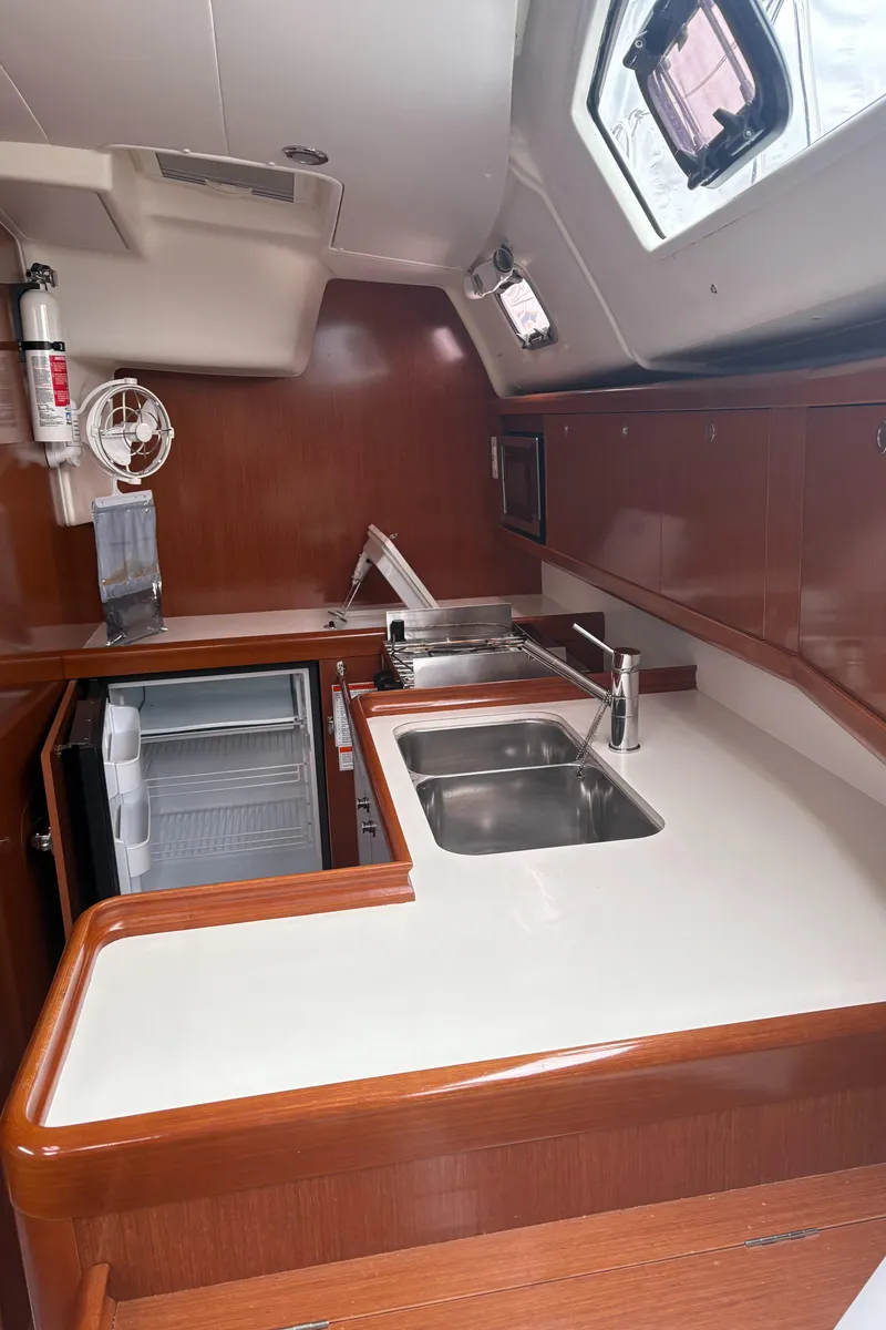 Slide: The Image of 2011 Beneteau Oceanis 40 yacht kitchen with sink, fridge, and wooden cabinetry. - 10
