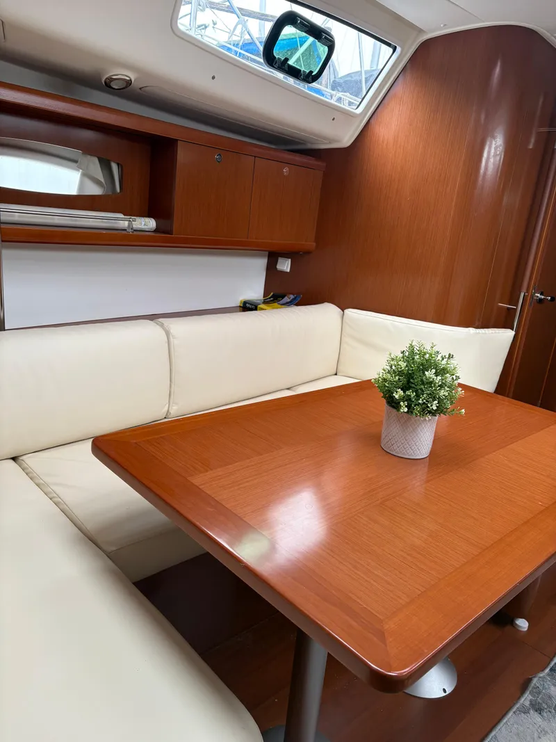 Slide: The Image of Interior of 2011 Beneteau Oceanis 40 sailboat with wooden table and white seating. - 16