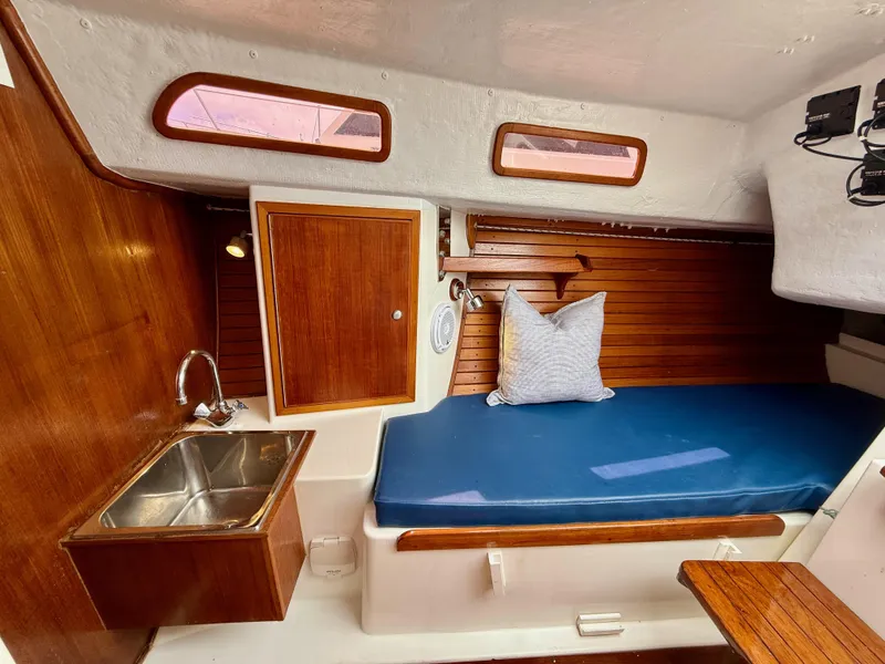 Slide: The Image of Cozy 2009 e Sailing Yachts e33 cabin interior with wooden finish and blue cushioned seating. - 23