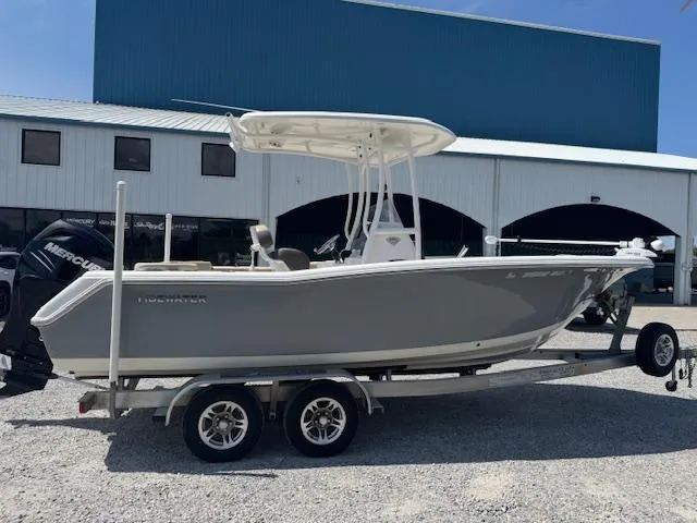 Slide: The Image of 2018 Tidewater 220 LXF boat on trailer, parked outside a blue and white building. - 12