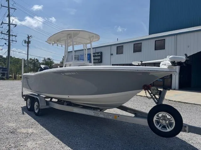 Slide: The Image of 2018 Tidewater 220 LXF boat on trailer, parked outside a building under a clear sky. - 2