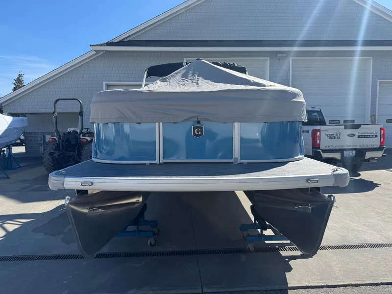 Slide: The Image of 2025 Godfrey Xperience Cruise pontoon boat with cover, parked outdoors. - 14