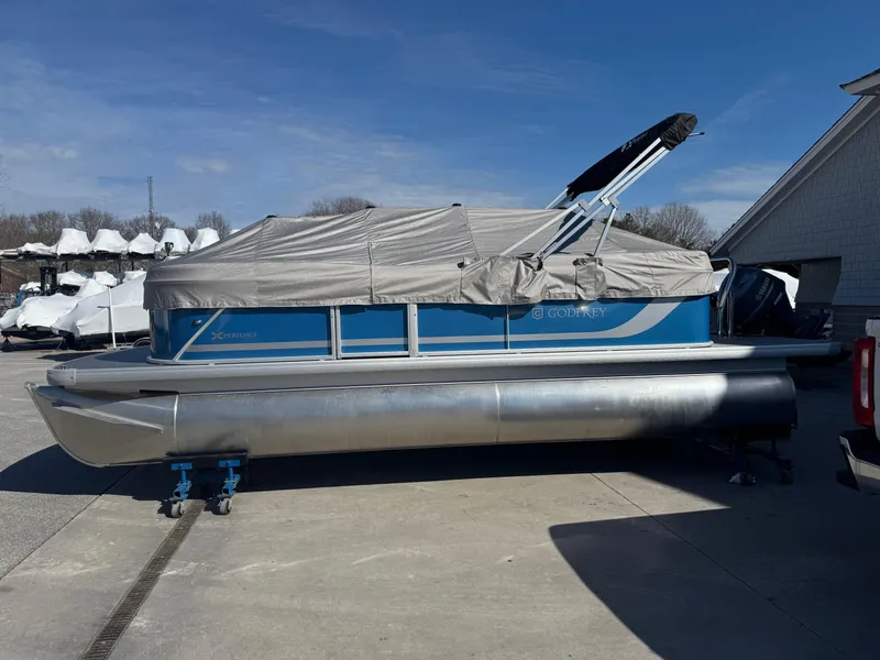 Slide: The Image of 2025 Godfrey Xperience Cruise pontoon boat with cover, parked outdoors on a sunny day. - 16