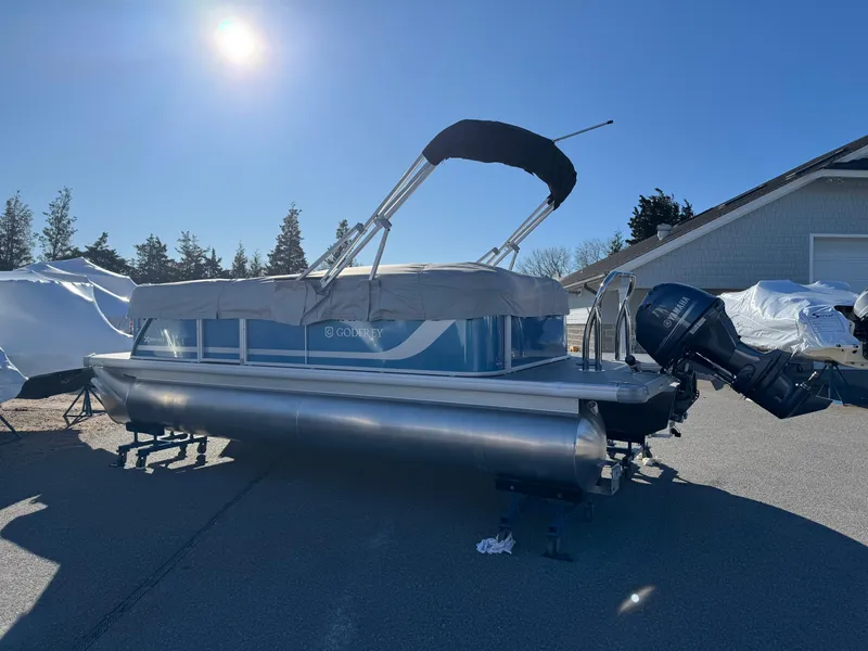 Slide: The Image of 2025 Godfrey Xperience Cruise pontoon boat with canopy, parked outdoors under clear blue sky. - 3