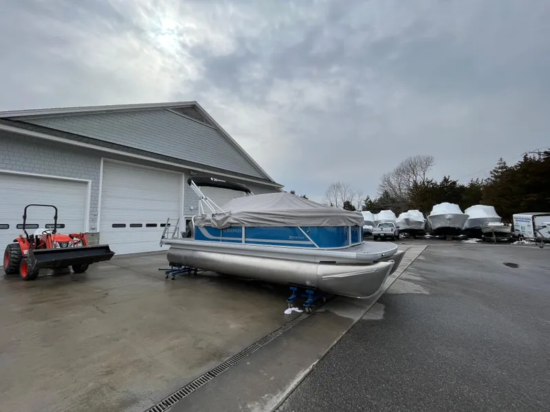Slide: The Image of 2025 Godfrey Xperience Cruise pontoon boat stored outdoors near a garage. - 5