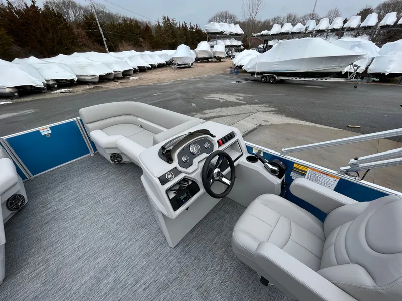 Slide: The Image of 2025 Godfrey Xperience Cruise boat interior with modern dashboard and seating, parked in a marina. - 7
