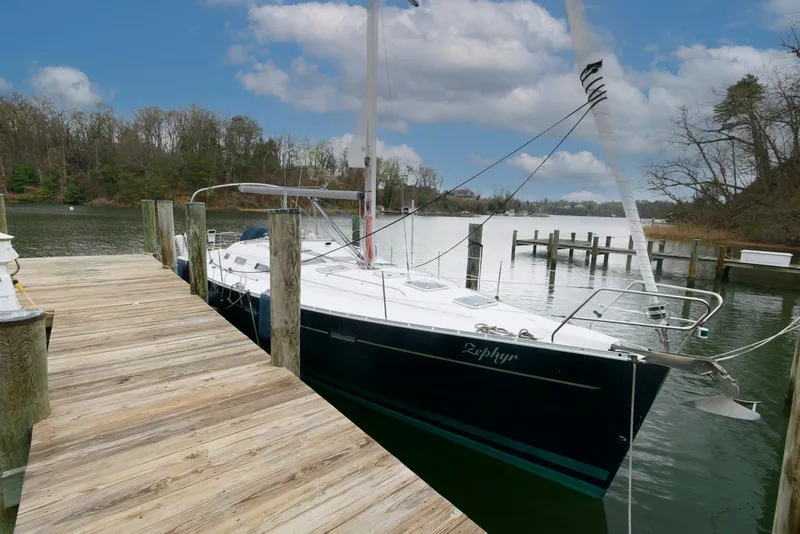 Slide: The Image of 2002 Beneteau 393 sailboat docked by a wooden pier on a calm lake. - 0