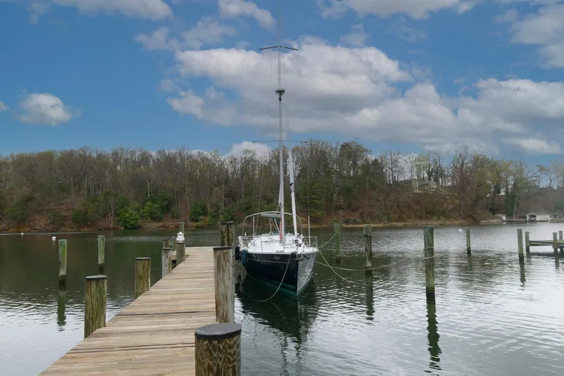 Slide: The Image of Sailboat docked at a wooden pier, Beneteau 393, 2002 model, under a partly cloudy sky. - 1