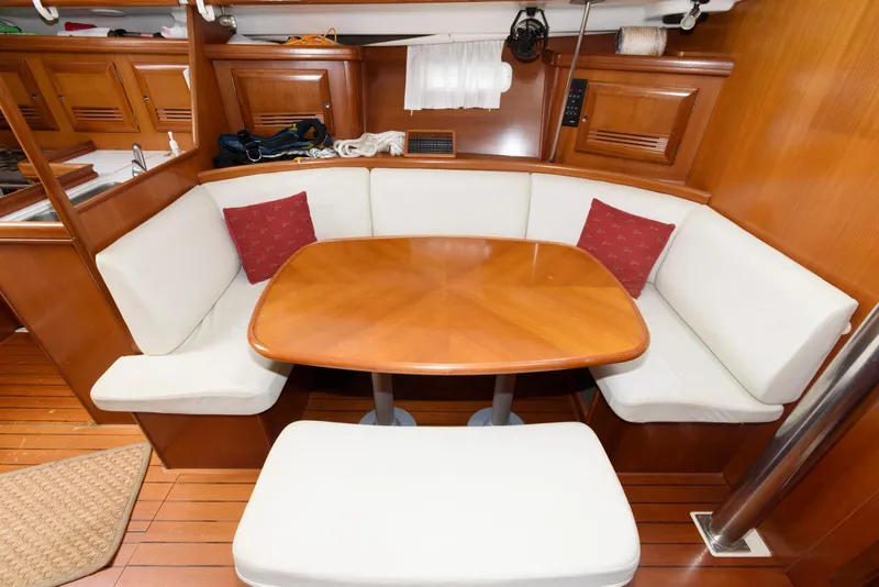 Slide: The Image of Interior of 2002 Beneteau 393 yacht with wooden dining table and white cushioned seating. - 10