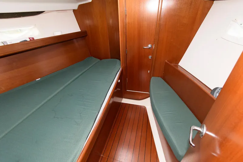 Slide: The Image of Interior cabin of 2002 Beneteau 393 sailboat with wooden finish and green cushions. - 15