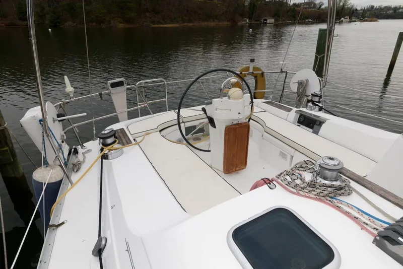 Slide: The Image of 2002 Beneteau 393 sailboat cockpit with steering wheel, ropes, and water view. - 7