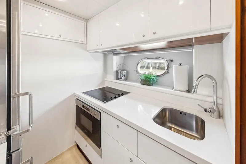 Slide: The Image of Compact yacht kitchen with modern appliances, white cabinetry, and a small porthole window. Baia PANTHER 80, 2003. - 45