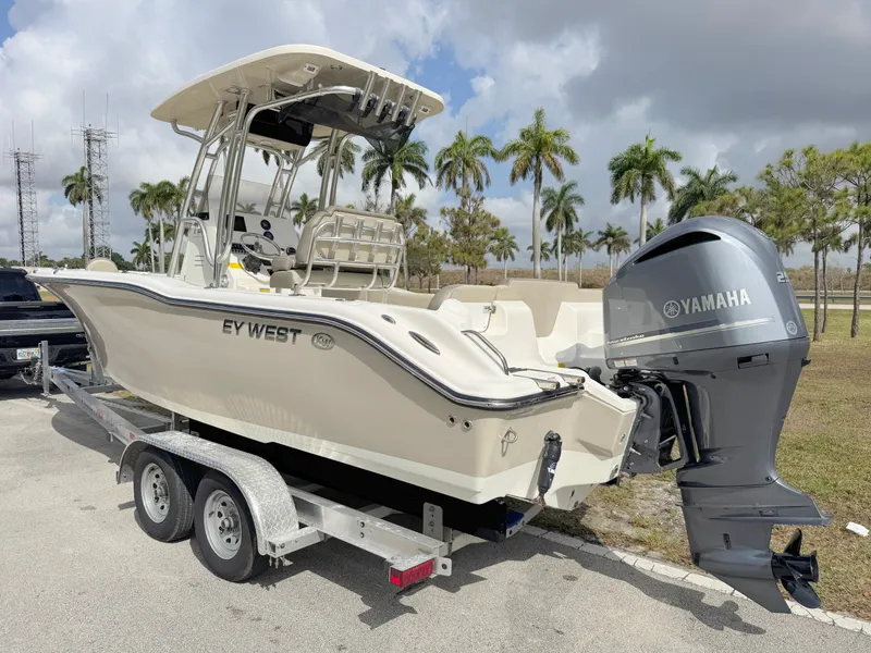 Slide: The Image of 2023 Key West 239 FS boat on trailer with Yamaha engine, parked near palm trees. - 2