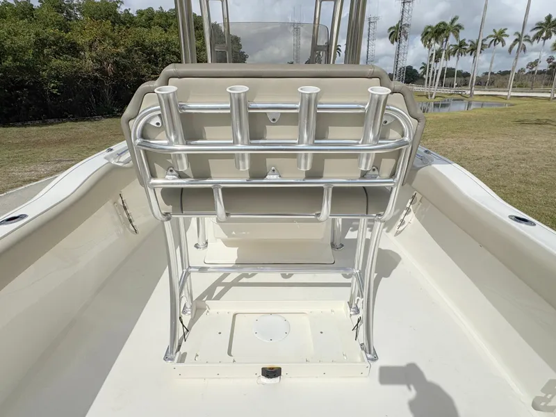 Slide: The Image of 2023 Key West 239 FS boat interior with rod holders and seating, surrounded by lush greenery. - 24