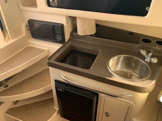 Slide: The Image of 2006 Grady-White Marlin 300 boat interior with kitchenette, sink, microwave, and stairs. - 15