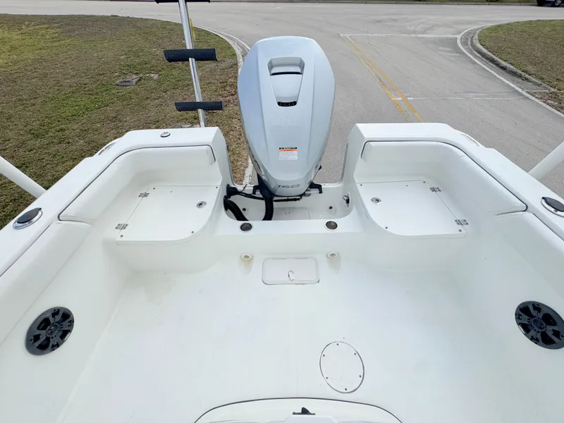Slide: The Image of 2016 Clearwater 2200 WI Center Console boat interior with motor, white seating, and storage compartments. - 20