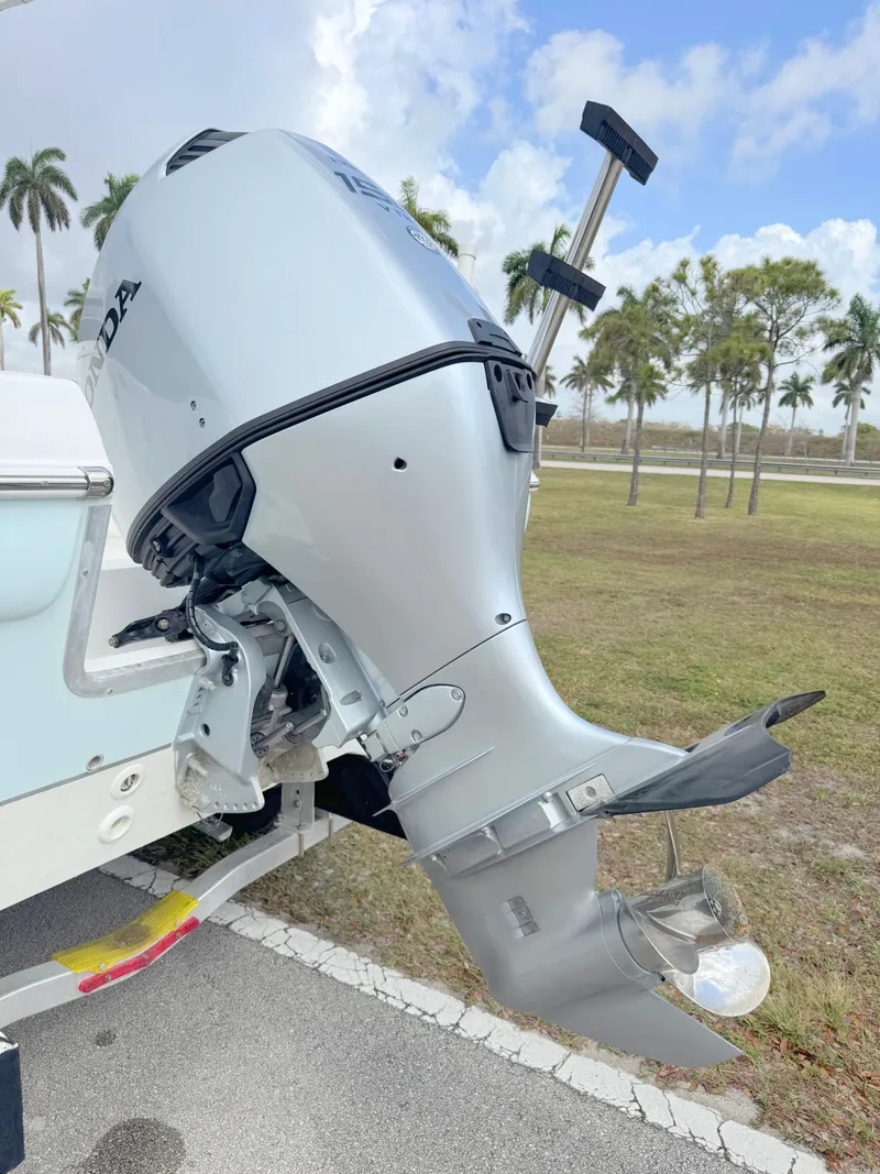 Slide: The Image of 2016 Clearwater 2200 WI Center Console boat engine, parked outdoors with palm trees in background. - 30