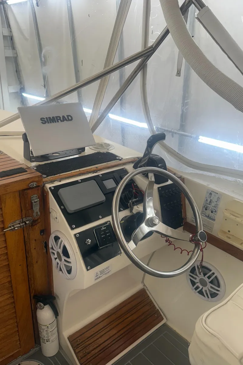 Slide: The Image of 1990 Albemarle 247 Express boat helm with steering wheel, Simrad display, and control panel. - 16