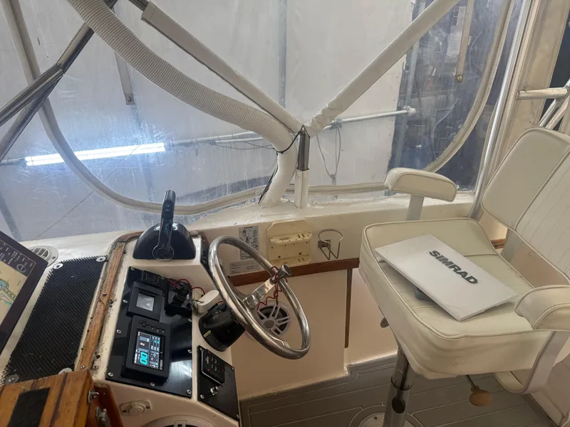 Slide: The Image of 1990 Albemarle 247 Express boat cockpit with steering wheel, controls, and a white captain's chair. - 18