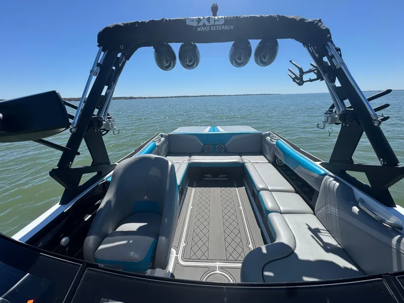 Slide: The Image of 2018 Axis T23 boat interior with seating, speakers, and wakeboard tower on a sunny day. - 10