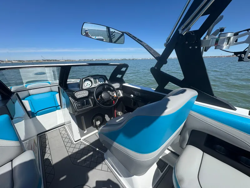 Slide: The Image of 2018 Axis T23 boat interior with blue and white seating, steering wheel, and dashboard on a sunny day. - 12
