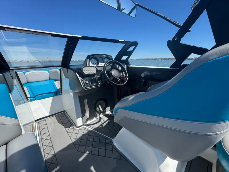Slide: The Image of 2018 Axis T23 boat interior with blue and gray seating, steering wheel, and dashboard. - 22