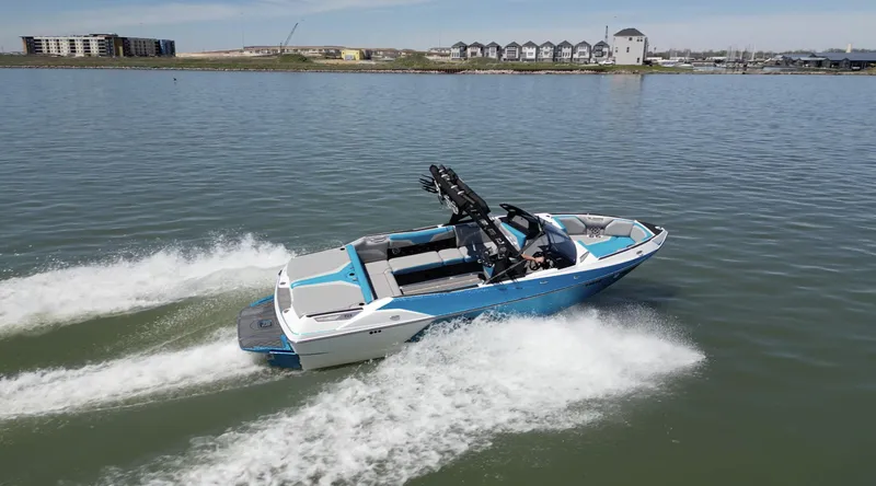 Slide: The Image of 2018 Axis T23 boat cruising on a calm lake with buildings in the background. - 34
