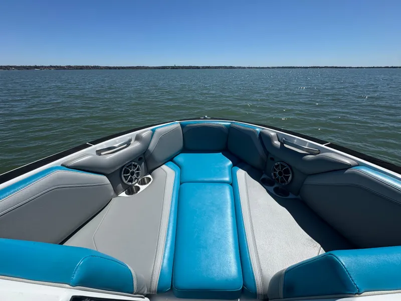 Slide: The Image of 2018 Axis T23 boat interior with blue and gray seating on a calm lake. - 7