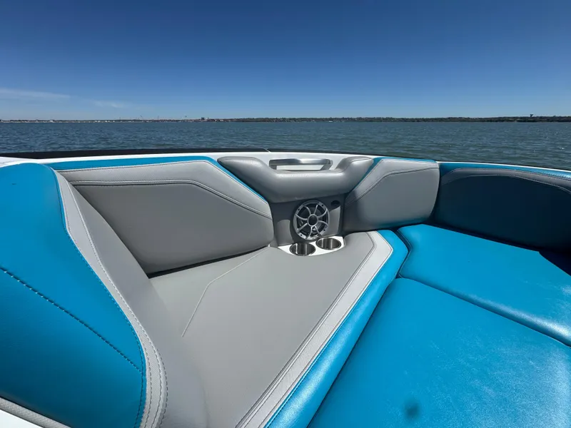 Slide: The Image of 2018 Axis T23 boat interior with blue and gray seating, cup holders, and speaker on a sunny day. - 8