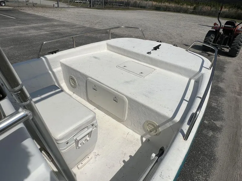 Slide: The Image of 2004 Sundance F17 boat interior with storage compartments and seating, parked on a gravel lot. - 12