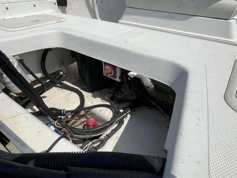 Slide: The Image of Open storage compartment in a 2004 Sundance F17 boat, showing wiring and components. - 13