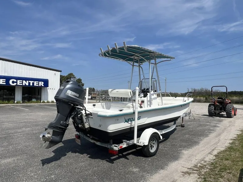 Slide: The Image of 2004 Sundance F17 boat on trailer with Yamaha outboard motor, parked near a center. - 6