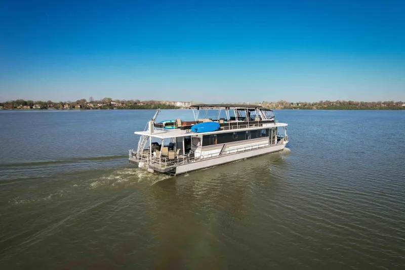 Slide: The Image of 1989 Sumerset houseboat cruising on a calm lake under a clear blue sky. - 10
