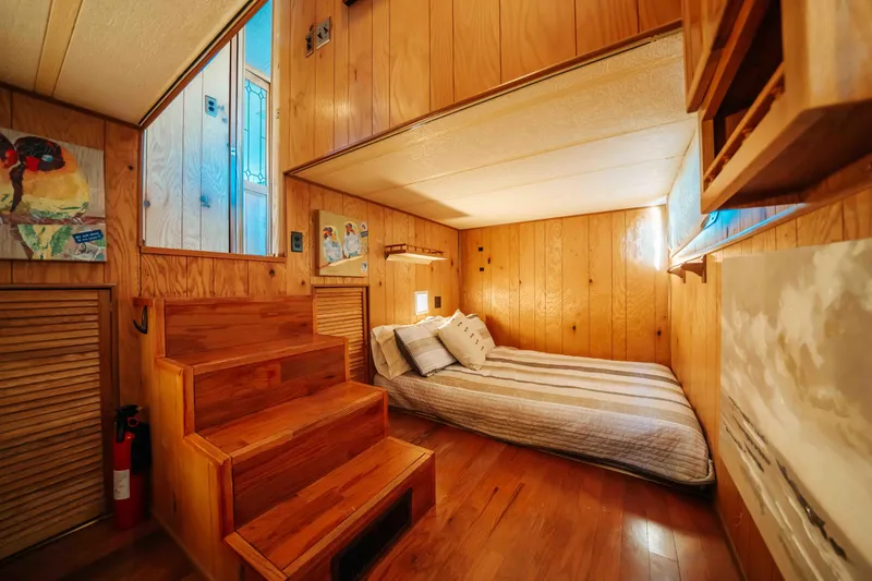 Slide: The Image of 1989 Sumerset houseboat interior with cozy wooden bedroom, bed, and stairs. - 18