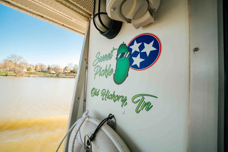Slide: The Image of 1989 Sumerset houseboat with "Sweet Pickle" decal, Old Hickory, TN, by a lake. - 23