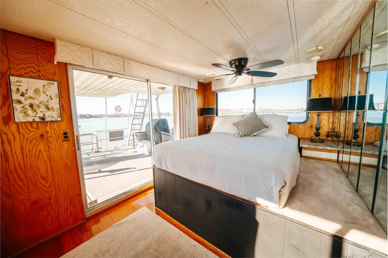 Slide: The Image of 1989 Sumerset houseboat bedroom with large bed, mirrored walls, and deck access. - 24