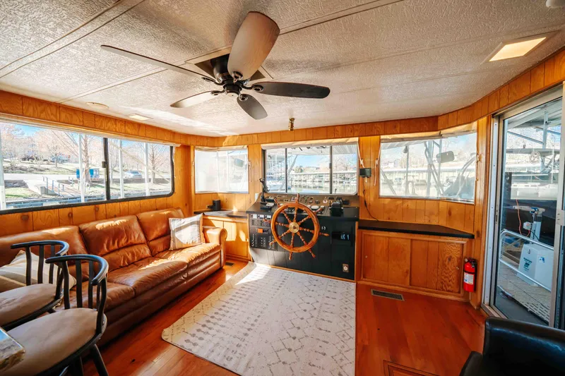 Slide: The Image of 1989 Sumerset houseboat interior with helm, leather sofa, and ceiling fan. - 47