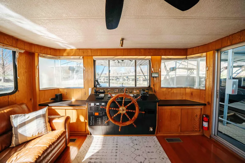 Slide: The Image of 1989 Sumerset houseboat interior with wooden helm, leather seating, and large windows. - 48