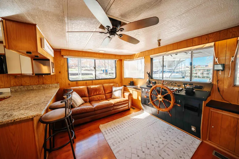 Slide: The Image of 1989 Sumerset houseboat interior with cozy seating, wooden helm, and modern kitchen area. - 49