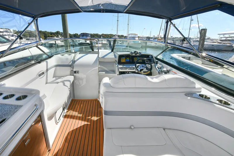 Slide: The Image of 2010 Formula 350 SS boat interior with white seating and wooden flooring at a marina. - 25