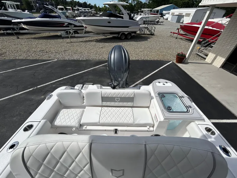 Slide: The Image of 2025 Sea Fox 228 Commander boat interior with white seating and motor, in a marina setting. - 13