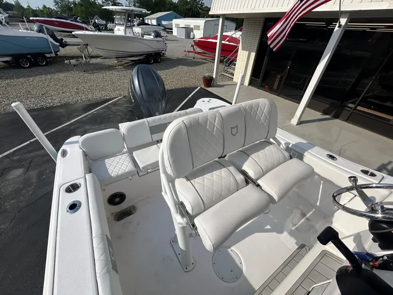 Slide: The Image of 2024 Sea Fox 228 Commander boat with white seating and steering wheel, parked outdoors. - 10