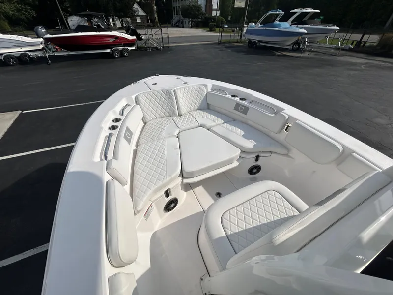 Slide: The Image of 2024 Sea Fox 228 Commander boat with white cushioned seating in a showroom. - 14