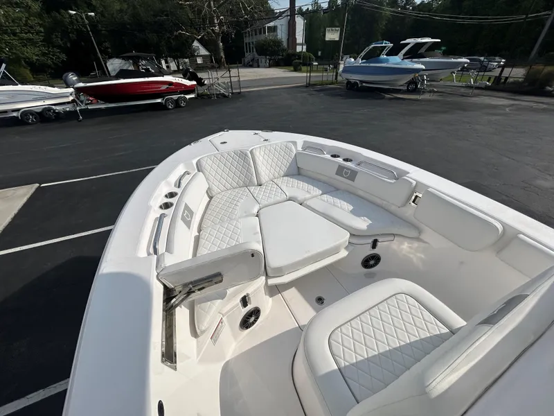 Slide: The Image of 2024 Sea Fox 228 Commander boat with white seating and spacious deck in a parking lot. - 15